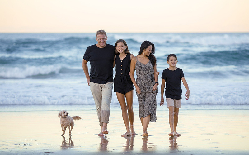 happy family and their dog walking together on the beach in jupiter