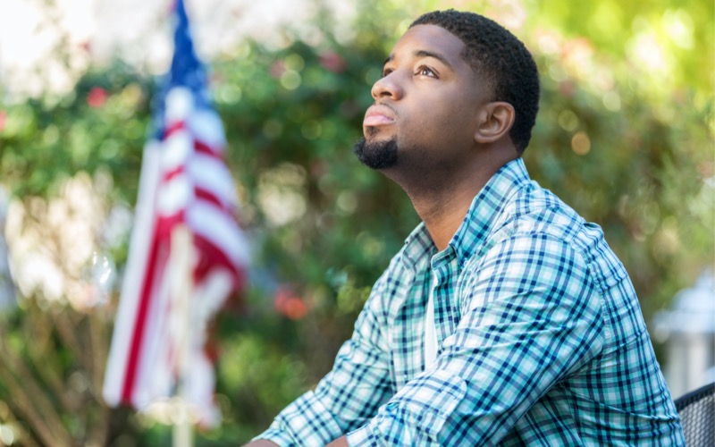 man with american flag in background representing a person with ptsd or trauma