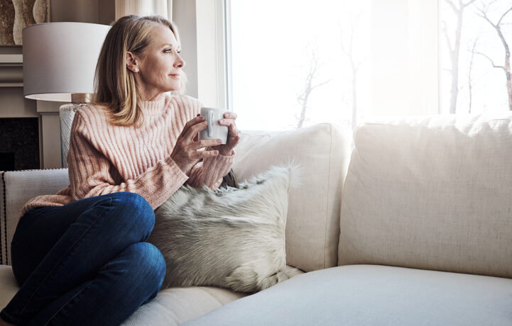 happy woman holding a coffee cup and looking out a window